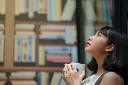 Jeune femme tenant sa tasse de café dans une bibliothèque