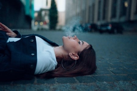 Femme allongée dans la rue fumant une cigarette