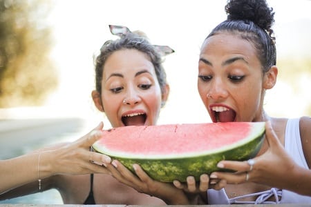 Deux jeunes femmes croquent à pleine dents une pastèque