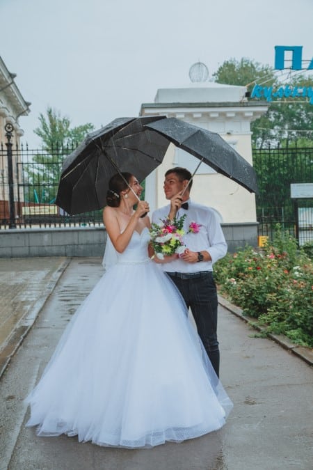 Couple de jeunes mariés sous la pluie