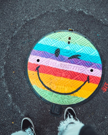 Smiley multicolore peint sur une plaque d'égout